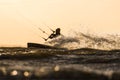 Silhouette of Kitesurfer riding in sunset conditions with backlit spray of water