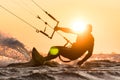 Silhouette of kitesurfer riding in sunset conditions with sun next to the riders head