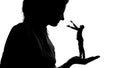 Silhouette of lady holding tiny male admirer in hand, women power, domination Royalty Free Stock Photo