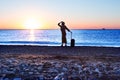 Silhouette of Lady staying on Sea Surf holding Travel Suitcase