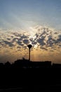 Silhouette of a lantern against the background of dawn over the city. Sun rays through the clouds Royalty Free Stock Photo