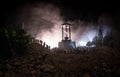 Silhouette of a large crowd of people in forest at night standing against a big hourglass with toned light beams on foggy backgrou Royalty Free Stock Photo