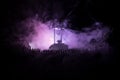 Silhouette of a large crowd of people in forest at night standing against a big hourglass with toned light beams on foggy backgrou Royalty Free Stock Photo