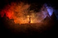 Silhouette of a large crowd of people in forest at night standing against a big hourglass with toned light beams on foggy backgrou Royalty Free Stock Photo