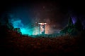 Silhouette of a large crowd of people in forest at night standing against a big hourglass with toned light beams on foggy backgrou Royalty Free Stock Photo