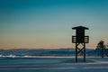 Silhouette of lifeguard tower in famous Spain holiday destination beach. Mountains and city in the background with sunset light Royalty Free Stock Photo