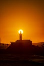 Silhouette of a lighthouse against a beautiful and dramatic orange sunset