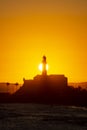 Silhouette of a lighthouse against a beautiful and dramatic orange sunset