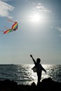 Silhouette of a little boy with flying kite on the background of the sea and sky Royalty Free Stock Photo