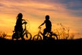 Silhouette little boy and little girl riding bike on sunset Royalty Free Stock Photo
