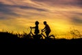 Silhouette little boy and little girl riding bike on sunset Royalty Free Stock Photo