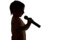Silhouette of little boy singing karaoke into microphone Royalty Free Stock Photo