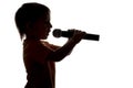 Silhouette of little child singing karaoke into microphone Royalty Free Stock Photo