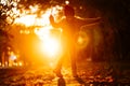 Silhouette of little girl with feather in hand, dancing in setting sun