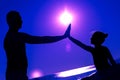 Silhouette of little girl with her father, palms of hands are raised to each other against the background of sunset