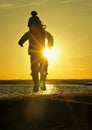 Silhouette of Little girl jumping on the ocean shore in backlight sunset.