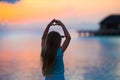 Silhouette of little girl making heart at sunset on the beach