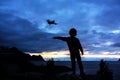 Silhouette of little toddler child, catching drone in the air, standing on a rock, splendid beautiful mountain landscape from