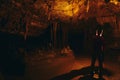 Silhouette lone person in cave with one light source stalagmites and stalactites