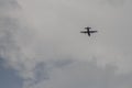 Silhouette of a lone plane in a gray sky with clouds