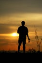 Silhouette of a lonely man holding a beer glass looking at the sunset