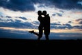 Silhouette lovely couple in a field at sunset with a dramatic sky