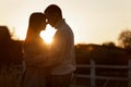 Silhouette of loving couple couple at sunset is hugging and touching nose to nose outdoors at park. Young man and Royalty Free Stock Photo