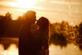 silhouette of loving couple hugging on the lake at sunset. Beautiful young couple in love walking on the shore of the Royalty Free Stock Photo