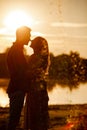 Silhouette of loving couple hugging on the lake at sunset. Beautiful young couple in love walking on the shore of the lake at Royalty Free Stock Photo