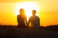 Silhouette of a loving couple at sunset sitting on sand on the beach, the figure of a man and a woman in love, a romantic scene in Royalty Free Stock Photo