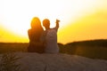 Silhouette of a loving couple at sunset sitting on sand on the beach, the figure of a man and a woman in love, a romantic scene in Royalty Free Stock Photo