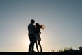 Silhouette of loving young couple hugging at sunset on background of cloudless sky in evening, full length. Royalty Free Stock Photo