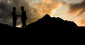 Silhouette male architects shaking hands on mountain against cloudy sky during sunset