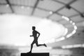 Silhouette of a Male Athlete, a Dedicated Runner, Showcasing Tenacity Amidst the Serene Evening Glow of a Modern Sports Stadium