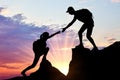 Silhouette of a male climber giving a helping hand to a woman