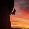 Silhouette male climber rock climbing pulling up with both hands. Sunset orange sky on background. Low angle. Copy space Royalty Free Stock Photo