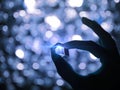 Silhouette Of A Male Hand Holding A Glass Cube With Blue Technology Lighting Illuminated Effected And Bokeh Background. Selected