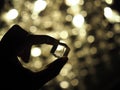 Silhouette Of A Male Hand Holding A Glass Cube With Bokeh Background. Selected Focus