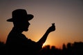 Silhouette male in hat showing korean heart at sunset