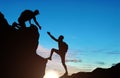 Silhouette of a male mountaineer giving a helping hand to his partner