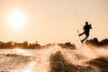 silhouette of male rider holding rope and making extreme jump on wakeboard over splashing water. Royalty Free Stock Photo