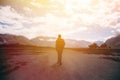 Silhouette of male traveler with backpack walking against the sunlight in mountain highland area Royalty Free Stock Photo