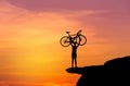 Silhouette the man in action lifting bicycle above his head stand on top of the mountain with sunset Royalty Free Stock Photo