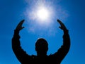 Silhouette of a man against the background of the sun and blue sky. Hands are raised up to the sun Royalty Free Stock Photo