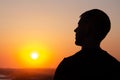 Silhouette of man against sunset sky. Person stands with his back against background of yellow sky with copy space. Male admires Royalty Free Stock Photo