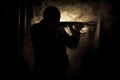 Silhouette of man with assault rifle ready to attack on dark toned foggy background or dangerous bandit in black wearing balaclava Royalty Free Stock Photo