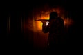 Silhouette of man with assault rifle ready to attack on dark toned foggy background or dangerous bandit in black wearing balaclava Royalty Free Stock Photo