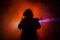 Silhouette of man with assault rifle ready to attack on dark toned foggy background or dangerous bandit in black wearing balaclava Royalty Free Stock Photo