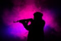 Silhouette of man with assault rifle ready to attack on dark toned foggy background or dangerous bandit in black wearing balaclava Royalty Free Stock Photo