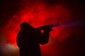Silhouette of man with assault rifle ready to attack on dark toned foggy background or dangerous bandit in black wearing balaclava Royalty Free Stock Photo